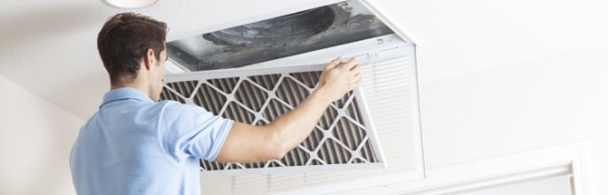 Man replacing air filter to improve indoor air quality